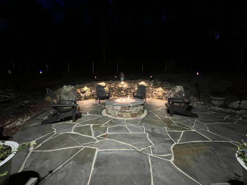 Beautifully lit landscape design in Etowah, NC, featuring illuminated wooden steps leading up a hillside, bordered by gravel pathways and accented with modern outdoor lighting for an elegant and functional aesthetic.