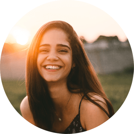 Smiling woman outdoors during sunset, embodying joy and satisfaction, reflecting the positive experiences of Laughter Family Hardscapes' landscaping services.