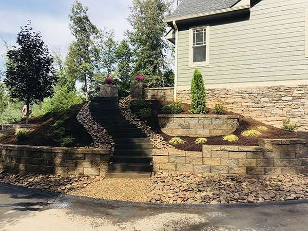 Custom hardscaping project featuring stone steps, landscaped garden beds, and decorative plants in Asheville, NC.