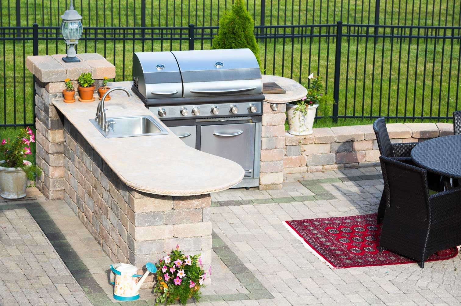 Outdoor kitchen with a built-in stainless steel grill and sink, surrounded by decorative masonry stonework, showcasing professional masonry services in Etowah, NC.