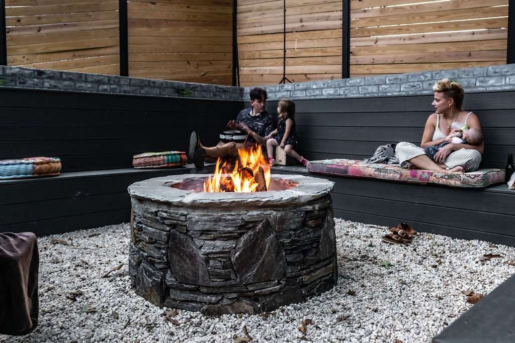Cozy outdoor seating area featuring a stone fire pit surrounded by family, showcasing a stylish hardscaping design by Laughter Family Hardscapes in Asheville, NC.
